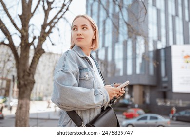 A young handsome girl businesswoman with a business appearance looks and talks on the phone in the city on a summer day and smiling