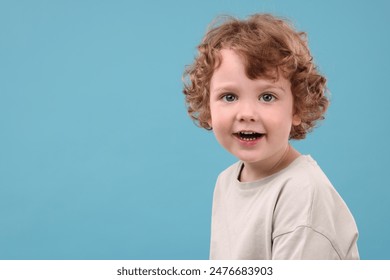 Potret anak laki-laki kecil yang lucu dengan latar belakang biru muda, ruang untuk teks