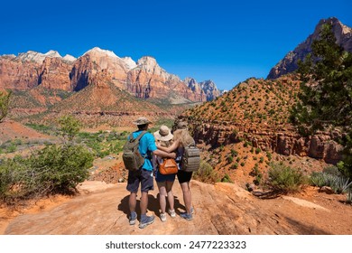 Família no topo da montanha apreciando a bela vista em uma viagem de caminhada em Utah. Amigos abraçados olhando para a paisagem da montanha. Trilha Watchman. Parque Nacional de Zion, Springdale, Utah, EUA