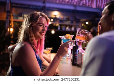 Beautiful young couple having fun, drinking alcohol cocktail in a bar. Attractive friend man and woman feeling happy and relax having a party, drink a glass of beer to celebrating event at night club.