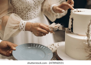 Az esküvői torta. A menyasszony és a vőlegény késsel levágott egy darab tortát. Az ifjú házasok keze levágta az esküvői torta első darabját.