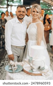 Az esküvői torta. A menyasszony és a vőlegény késsel levágott egy darab tortát. Az ifjú házasok keze levágta az esküvői torta első darabját.