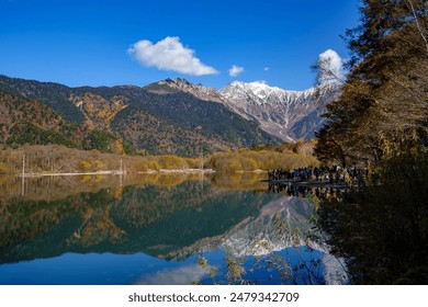 Touristes observant la chaîne de montagnes Hotaka depuis l'étang Taishoike, Kamikochi, Japon, dans le feuillage d'automne, Nagano, Japon.
