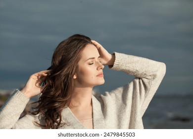 Štýlová brunetka mladá dáma model na morskej pláži. Krása ženy s make-upom a dlhým tmavým vlnitým účesom vonku. Nálada emócií pokoja, cestovanie, sezóna a koncept dovolenky