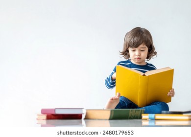 Concetto di istruzione e ritorno a scuola. Ritratto di un bambino felice dell'asilo che impara a leggere un libro sul pavimento. I bambini in età prescolare si divertono studiando e facendo i compiti a casa.