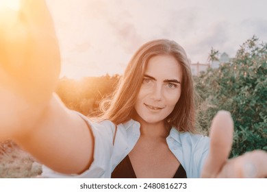 Amber Golden Hour Nga afër një grua e larë në dritën e orës së artë duke bërë selfie në perëndimin e diellit në parkun veror. Turisti i lumtur kënaqet duke bërë foto selfie jashtë për kujtime