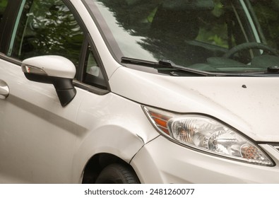 Espelho lateral de um carro branco com danos no para-lama.