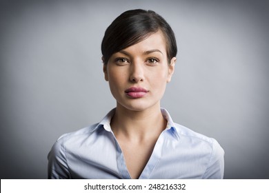 Close up portrait of serious, confident businesswoman looking straight, isolated on grey background.