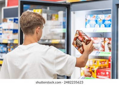 Mann wielt gefruer Liewensmëttel aus engem Supermarché Frigo. Eis,