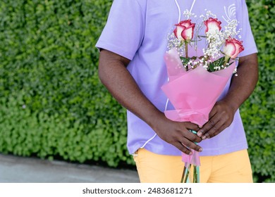 Unrecognizable man wearing headphones and holding a bouquet of roses.
