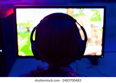 คนๆ หนึ่งกำลังนั่งอยู่หน้าจอคอมพิวเตอร์ สวมหูฟัง และกำลังเล่นวิดีโอเกม หน้าจอสว่างขึ้น แสดงภาพเกมที่กำลังเล่นอยู่ และมองเห็นเงาของบุคคลนั้นได้