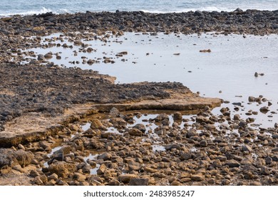 Rocky coast with a body of water in the background. The water is calm and the rocks are scattered throughout the area. Atlantic ocean low tide scenery