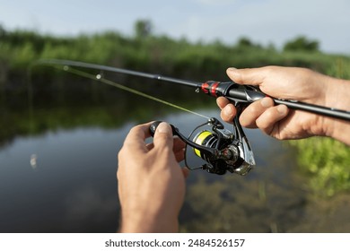 Pêche au brochet et à la perche dans un lac ou un étang. Nature sauvage en arrière-plan. Pêcheur avec canne et moulinet au bord de la rivière. Nature sauvage. Le concept d'une escapade rurale. Article sur la journée de pêche.