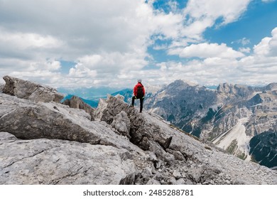 Excursionist femeie care stă în poziție de erou pe o stâncă sus pe vârful muntelui privind peisajul alpin într-o zi înnorată