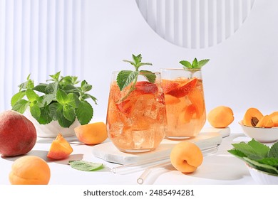 Thé glacé à la pêche ou cocktail à la menthe et aux abricots : une recette pour une boisson estivale rafraîchissante. Deux verres de limonade aux fruits de pêche sur une table basse, concept de régime détox et de perte de poids, menu