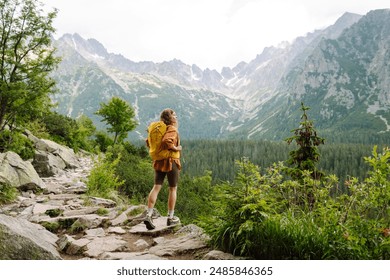 Active woman tourist with backpack enjoys the beautiful scenery of the majestic mountains. Travel, adventure. Concept of an active lifestyle.