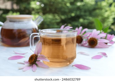 Čajni napitak s Echinacea purpurea (Echinacea purpurea) na svjetlosnom stolu. Koncept pripreme napitka od ehinaceje. Čaj od ehinacee. Pogled sa strane.