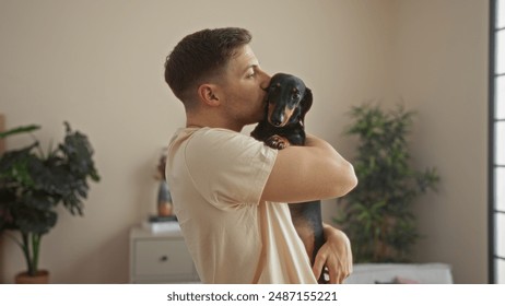 Um jovem hispânico segura e beija carinhosamente seu cão bassê em uma sala de estar aconchegante, cercada por plantas e iluminação suave, capturando um momento terno de amor e companheirismo.