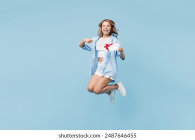 Full body young happy woman wears white top shirt casual clothes jump high hold gift certificate coupon voucher card for store isolated on plain pastel light blue cyan background. Lifestyle concept