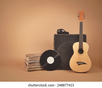 音楽やバンドのコンセプト用に、茶色の背景に古いビニールレコードとアンプ付きのアコースティック木製ギターのスタックが分離されています。