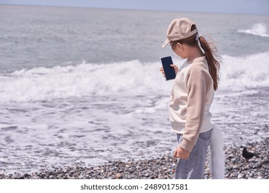 Un niño con cola se toma fotos a sí mismo. Una niña quadrobra se toma un selfie en la orilla del mar. El concepto de entretenimiento donde los niños se disfrazan de animales. Foto de alta calidad