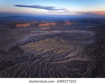 Widok z lotu ptaka na czarne wzgórza Badlands w stanie Utah, USA o zachodzie słońca ze złotym niebem na horyzoncie