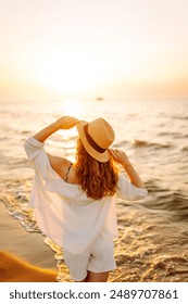 Happy woman on beach in summer style fashion trend outfit carefree and happy, feeling freedom. Seascape at sunset with beautiful sky. Travel, weekend, relax and lifestyle concept.