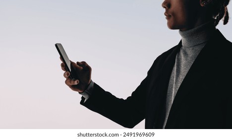 Silhouette eines jungen Mannes, der sein Handy zum Lesen und Schreiben von Textnachrichten in einer Social-Media-App verwendet. Der Studiohintergrund verleiht diesem Bild von vernetzter Kommunikation und Lebensstil eine stilvolle Note.