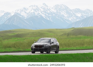 Expensive black SUV on a scenic road with lush green fields