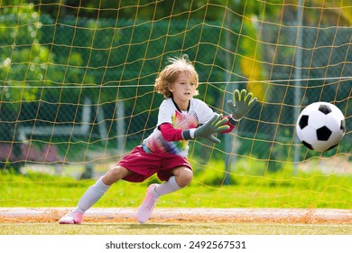 Niño jugando al fútbol. Niños jugando al fútbol en una cancha al aire libre. Niño pequeño pateando una pelota en un parque de verano. Actividad saludable para niños pequeños. Equipo del club deportivo escolar. Liga juvenil de fútbol.