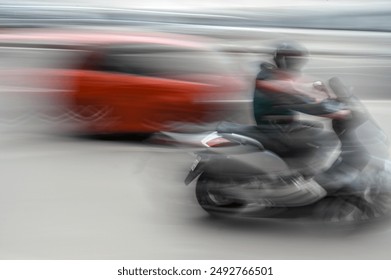 Un motard sur une moto roule vite à travers la ville, photo floue. Conduire une moto. Voiture et moto dans la rue.