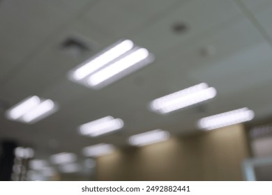 ฺDesenfoque del techo de la sala de oficina con iluminación. Techo suspendido con lámparas LED cuadradas en la oficina. Concepto de decoración de interiores