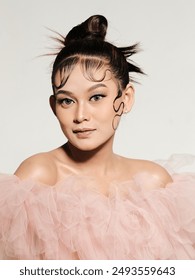 seorang model bergambar memakai pengantin perempuan berwarna peach dengan bahu terbuka menjadikan model itu kelihatan lebih seksi dan sentuhan solekan serta dandanan rambut menjadikan model itu kelihatan lebih cantik dan anggun.