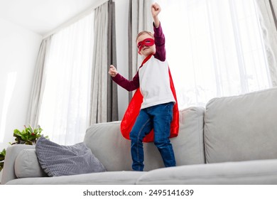 穿着超级英雄服装的男孩站在沙发上