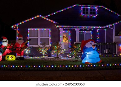Dekorasi Natal yang indah di luar rumah pada malam hari. Rumah dihiasi dengan lampu biru untuk Natal. Fokus selektif, latar belakang kabur