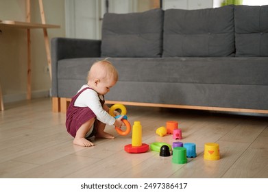 il bambino gioca con i giocattoli. insegnare ai bambini il concetto di sogno del bambino. il bambino sul pavimento della casa gioca con una piramide e dei cubi giocattoli stile di vita sviluppo delle capacità motorie fini