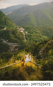 유럽의 알프스 산맥의 푸른 산의 파노라마를 배경으로 모자, 부츠, 하얀 긴 드레스를 입은 긴 금발 머리의 소녀. 라벤더 꽃다발을 든 소녀, 선글라스를 쓰고