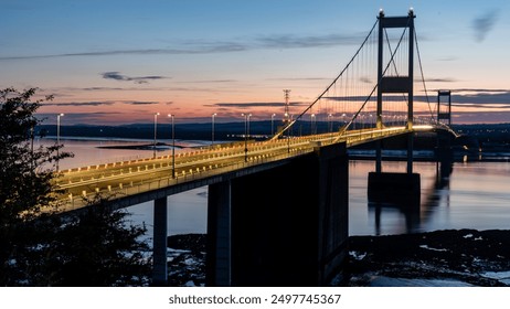 Die Severn Bridge wird bei Sonnenuntergang durch Lichtspuren vorbeifahrender Autos beleuchtet