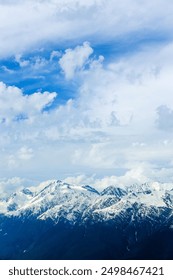 Ehrfurchtgebietende Aussicht auf schneebedeckte Berggipfel unter blauem Himmel mit weißen Wolken bei Rosa Khutor in Krasnaja Poljana, Sotschi, Russland. Gipfel der kaukasischen Berge