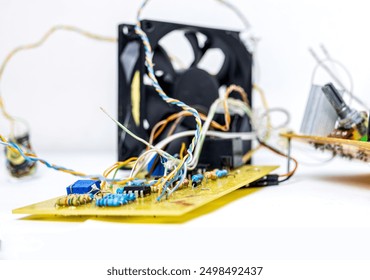 Overblijfselen, ruïnes van een elektrisch temperatuurregelcircuit met ventilator, potentiometers, weerstanden, UTP-kabels, jumpers en LM35-sensor, op geel breadboard en PCB. Witte achtergrond.