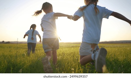 group of children run across the field on the grass. happy family kid dream concept. children running in a field with tall grass. girls holding hands in lifestyle the foreground legs close up