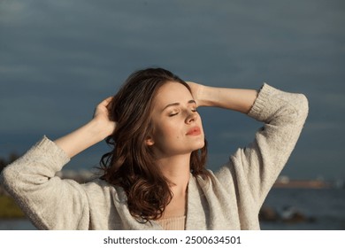 Slávna brunetka mladá dáma na morskej pláži. Krása ženy s make-upom a dlhým tmavým vlnitým účesom vonku. Nálada emócií pokoja, cestovanie, sezóna a koncept dovolenky
