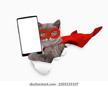 Schattige kitten in superheldenkostuum kijkt door het gat in wit papier en toont een grote smartphone met een leeg scherm. Lege ruimte voor tekst