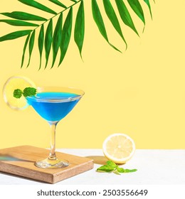 Coquetel de verão azul com menta e limão em fundo amarelo brilhante com folha de palmeira. Conceito criativo moderno. Coquetel lagoa azul com licor de curaçao.