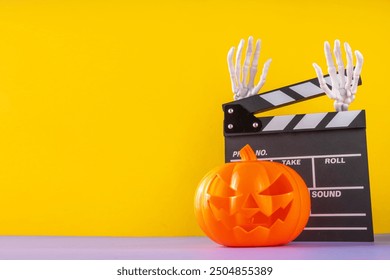 Horror movie, series night, Halloween cinema party with trick-or-treating sweets bucket, popcorn, movie clapperboard and Halloween decorations on high-colored background copy space