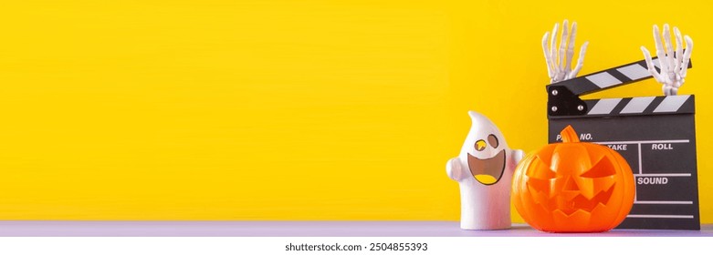 Horror movie, series night, Halloween cinema party with trick-or-treating sweets bucket, popcorn, movie clapperboard and Halloween decorations on high-colored background copy space