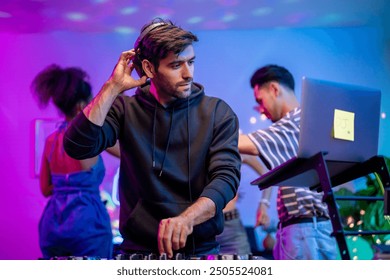 Artista DJ caucásico joven que mezcla y hace scratch con el controlador de la mesa de mezclas. Músico DJ atractivo que se divierte mezclando música en la consola tocando botones y tocando música electrónica en una fiesta de neón.