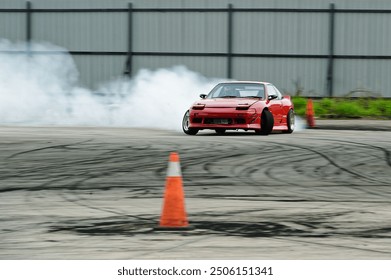 Makinë sportive e kuqe që lëviz, goma që digjet në pistën e asfaltit, lëvizja e shpejtësisë së turbullt me ​​gomën e rrotave që digjet me tymin e gomës, gara me vetura sportive me motor drift