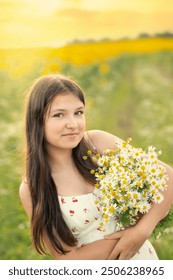 linda adolescente com cabelos longos e um buquê de margaridas nas mãos em um prado florido em uma noite de verão. Retrato gentil