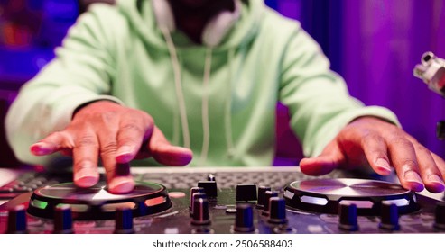 Primer plano de un DJ con las manos en la mesa de mezclas. Un hombre africano utiliza un equipo de DJ para crear música moderna para una fiesta.